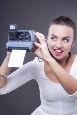 Beyaz esmer kadın anlık fotoğraf makinesi ve yazıcı ile gülümseyen portresi.