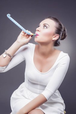 Kutlamalar kavramları. Çok gülümseyen beyaz esmer parti düdük üfleme.