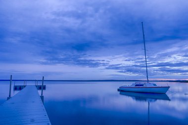 Braslav göl günbatımı zaman Belarus pitoresk görüntüsü. Arka planda küçük yelkenli tekne