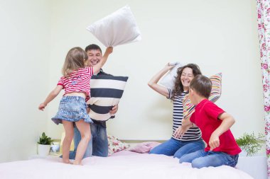 Dört oynak komik yastık savaşı kapalı yatağa sahip genç Beyaz aile