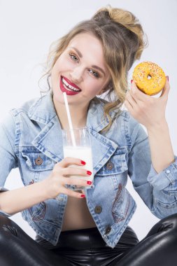 Sarışın kız fincan süt ve Doghnut Bagel.Eating pasta ve beyaz karşı poz ile eğleniyor