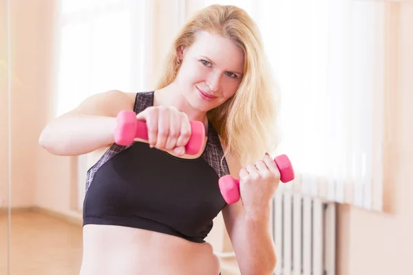 Sport, Fitness, Wellness and Lifestyle Concepts. Closeup of Caucasian Smiling Female Athlete Posing With Barbells In Gym Against Mirror Wall On Background. Horizontal Orientation
