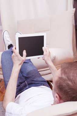 Tablet bilgisayar yere chat yapan adam. Kanepeye kaldırdı bacaklar