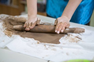 Atölyede kil oklava ile bir parçasını yayıyoruz önlük kadın profesyonel ellerin aşırı Closeup