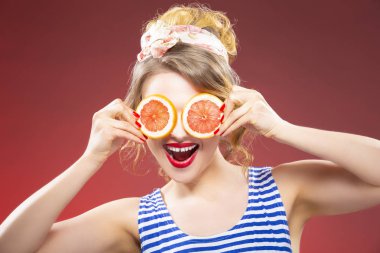 Gizleme gözleri önünde iki greyfurt dilim Beyaz sarışın. Kırmızı arka planı