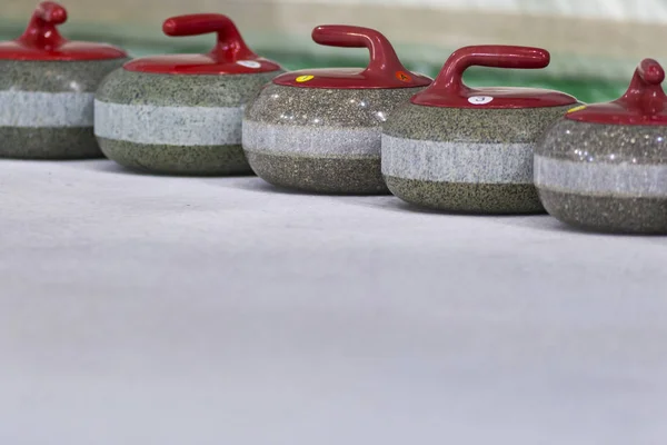 Sport Concepts. Closeup of Curling Red Handle Stones on Ice.