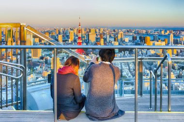 Romantic Young Couple Sitting Together on Top of Tokyo Scyscrapers