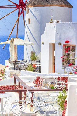 Seyahat Kavramları ve Fikirler. Yunanistan 'ın Santorini Adası' ndaki Oia ya da Ia 'daki İnanılmaz Yunan Geleneksel Evlerinin Resimli Manzarası. Arka plandaki Windmill ve Açık Hava Restoranı 'nda. Dikey resim