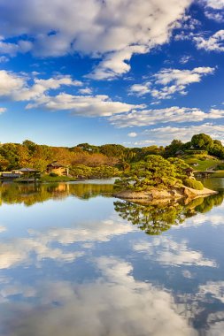 Japonya 'daki Okayama Korakuen Parkı' nda Kayo-no-ike Göleti ile geleneksel Japon Bahçesi. Altın Saat 'te Fotoğraf Çekildi. Dikey Resim Kompozisyonu