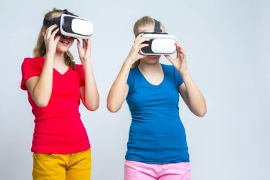 Sanal Gerçeklik Simülasyonu. Kafkasyalı İkiz Kızlar VR ile Oynuyor (Sanal Gerçeklik) Miğferler Birlikte Salonda. Yatay Görüntü