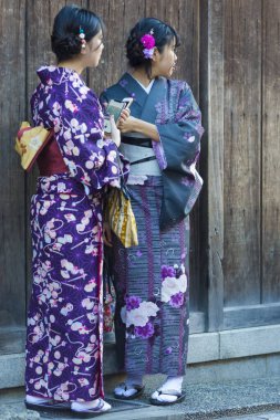 KYOTO, JAPONYA - 8 Kasım 2019: Japon Kadınlar Geyşa Kimonosu ile poz veriyor ve Japonya 'nın Kyoto sokaklarından birinde fotoğraf çekiyor.
