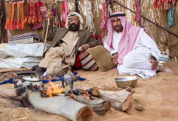 Two old emirati men warming themselves with bonfire from cold  in  Al Wathba Festival in Westrin Regin Abu Dhabi on December 9 2012