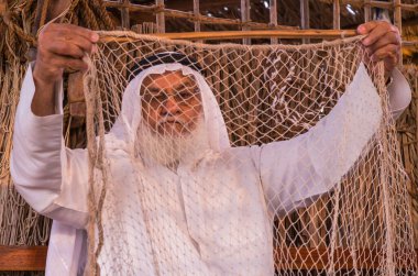 Yaşlı adam SHEIKH ZAYED FESTIVAL 22 Eylül 2014 tarihinde Abu Dhab, Birleşik Arap Emirlikleri 'nde geleneksel balık ağı örüyor.