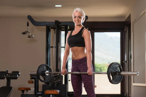 Fitness kvinna med skivstång tränar tillbaka inne i gymmet — Stockfoto