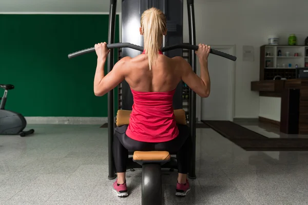 Jovem mulher fazendo exercício nas costas no centro de fitness — Fotografia de Stock