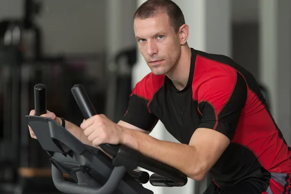 Fitness salonunda bisikletle sağlıklı adam — Stok fotoğraf
