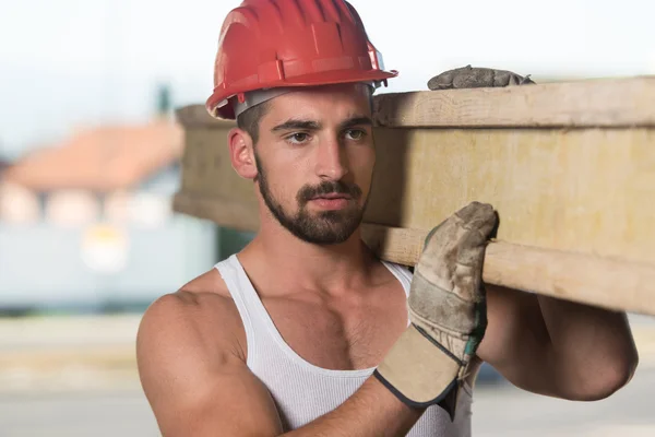 Jonge knappe bouwer met houten planken — Stockfoto