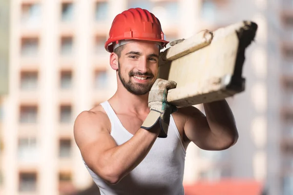 Junger gutaussehender Bauarbeiter mit Holzbohlen — Stockfoto
