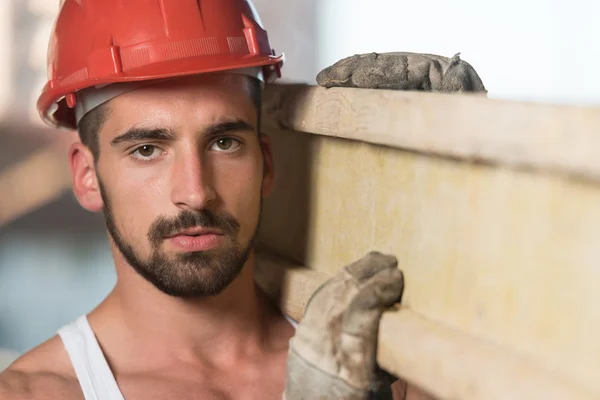 Joven constructor guapo con tablones de madera — Foto de Stock