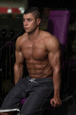 Kaslı adam trisepsler için ağır ağırlık egzersizi yapıyor.