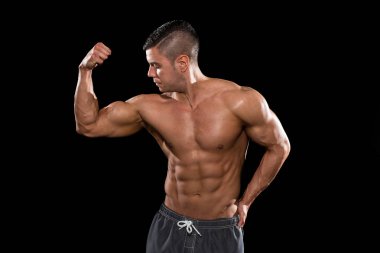 genç vücut geliştirmeci kasların esneme siyah blackground izole et.