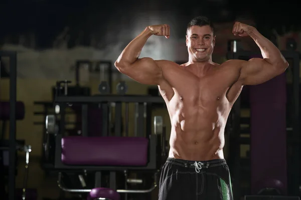 Мускулистый мужчина сгибает мышцы в спортзале — стоковое фото