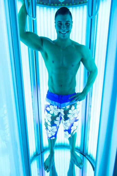 Joven musculoso hombre en solarium en salón de belleza — Foto de Stock