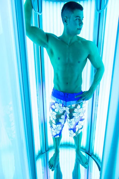 Joven musculoso hombre en solarium en salón de belleza — Foto de Stock