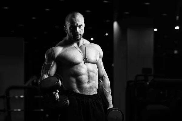 Hombre con sombrillas ejercitando bíceps en el gimnasio — Foto de Stock