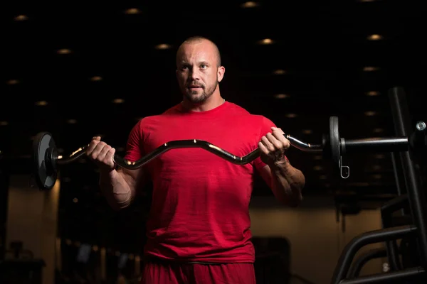 Modelo masculino musculoso ejercitando bíceps con barra — Foto de Stock