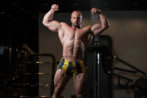 Bodybuilder homme posant dans la salle de gym — Photo