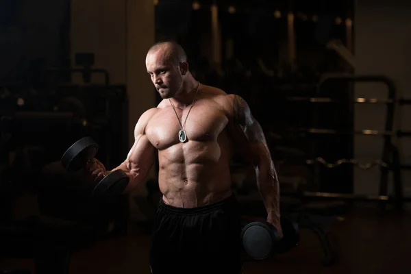 Hombre con sombrillas ejercitando bíceps en el gimnasio — Foto de Stock