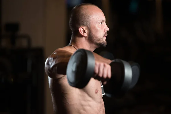 Bodybuilder trainieren Schultern mit Kurzhanteln — Stockfoto