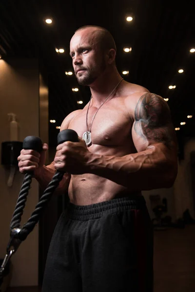 Hombre muscular ejercitando bíceps en la máquina de cable — Foto de Stock