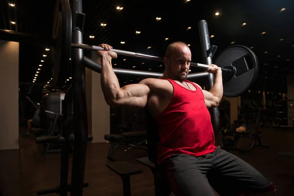 Kaslı adam omuz için ağır egzersiz yaparak — Stok fotoğraf