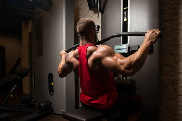 Ćwiczenia mięśni człowiek fitness z powrotem na maszynie — Zdjęcie stockowe