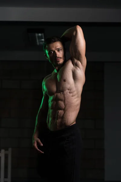 Musculoso hombre flexionando los músculos en el gimnasio — Foto de Stock