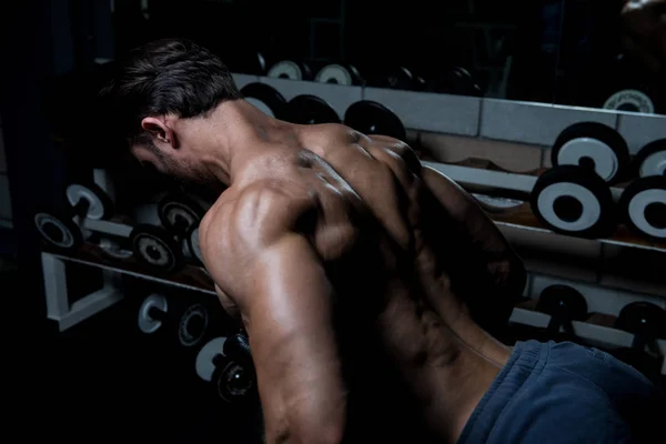 Muskulöser Mann trainiert Rücken mit Kurzhanteln — Stockfoto