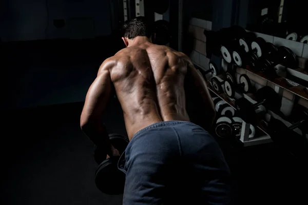 Muscoloso uomo esercizio indietro con manubri — Foto Stock
