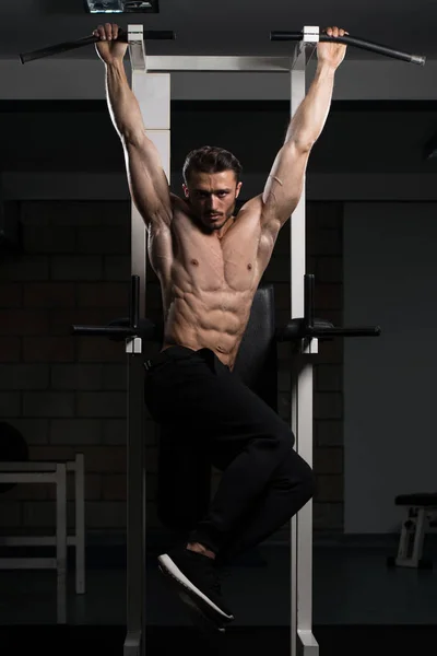 Jovem realizando pendurado perna levanta exercício — Fotografia de Stock