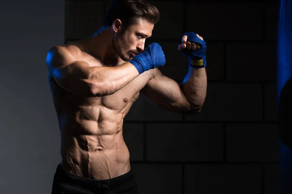 Boxer muscoloso senza camicia con sacco da boxe in palestra — Foto Stock