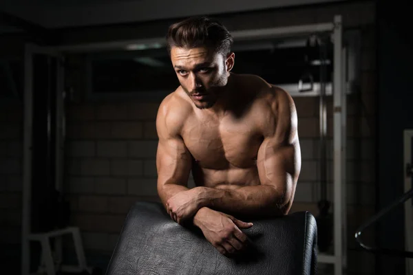 М'язистий чоловік після вправи відпочиває в тренажерному залі — стокове фото