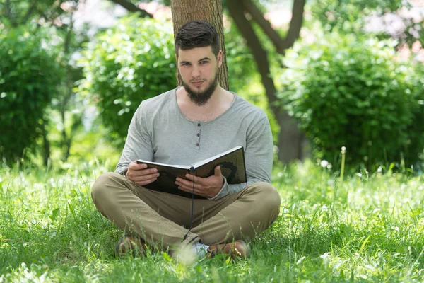 イスラム教徒の男性が公園でコーランを読む — ストック写真