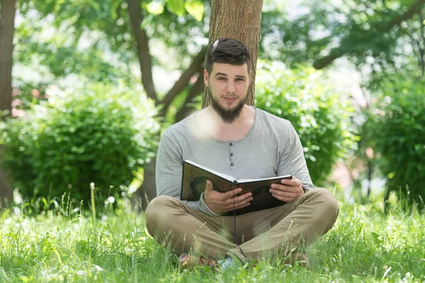 イスラム教徒の男性が公園でコーランを読む — ストック写真