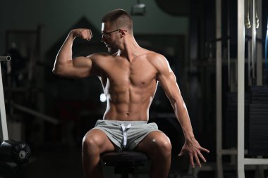 Salonda oturan ciddi vücut geliştirmeci giyen gözlük