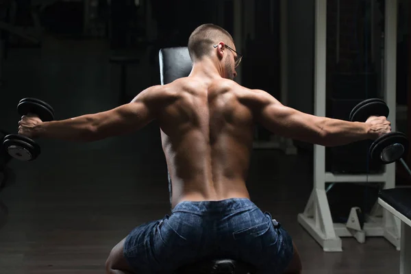 Homem muscular exercitando de volta com halteres — Fotografia de Stock