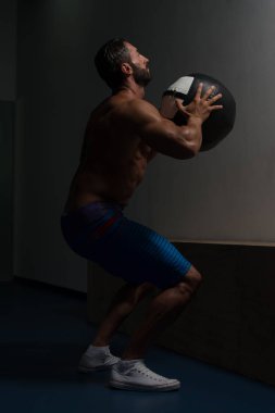 Kaslı adam medecine topu egzersizleri yapıyor