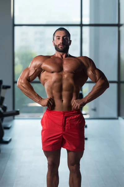 Gespierde man buigen spieren in de sportschool — Stockfoto