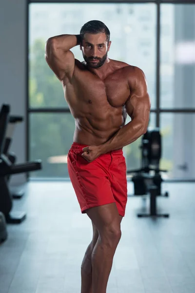 Construtor de corpo bonito que faz a dose lateral do peito — Fotografia de Stock