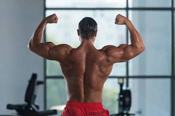 Muscular hombre flexión músculos trasero doble bíceps Pose —  Fotos de Stock